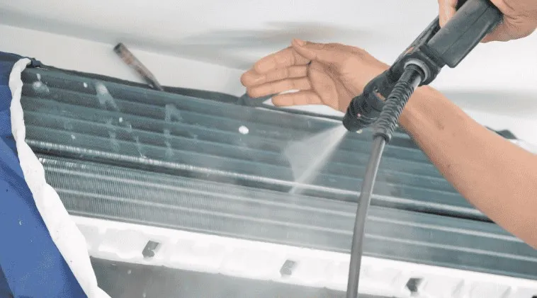 Teknisi membersihkan evaporator dengan alat steam bertekanan